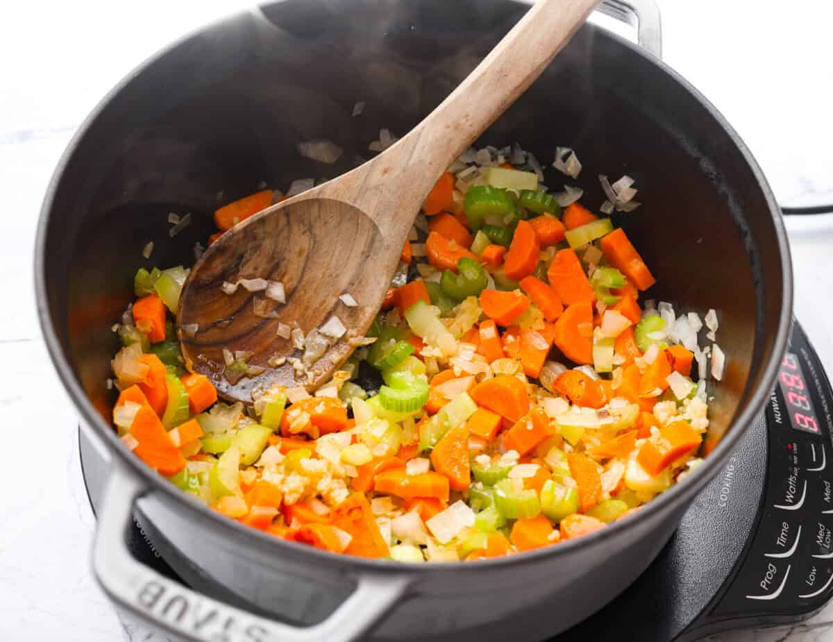 Carrots, onion, and celery cooking in a pot.