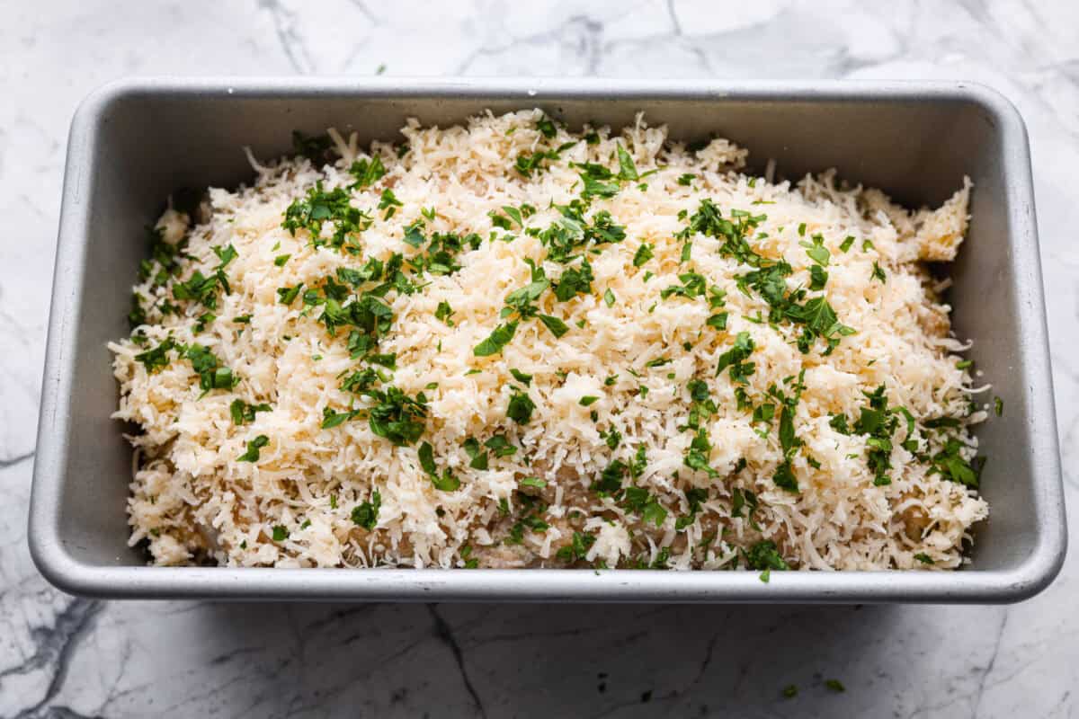 Parmesan and fresh parsley on top of the meatloaf ready to go in the oven.