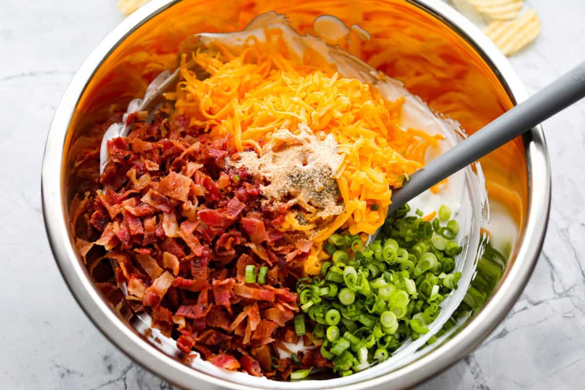 You need to stop what you’re doing and make this loaded baked potato dip right now! It’s creamy, cheesy, bacony perfection! It’s to die for. It's perfect for game day, parties, or to snack on while you catch up on your favorite show. Cheese, bacon, onions, garlic powder, salt, and pepper added to the cream cheese mixture.