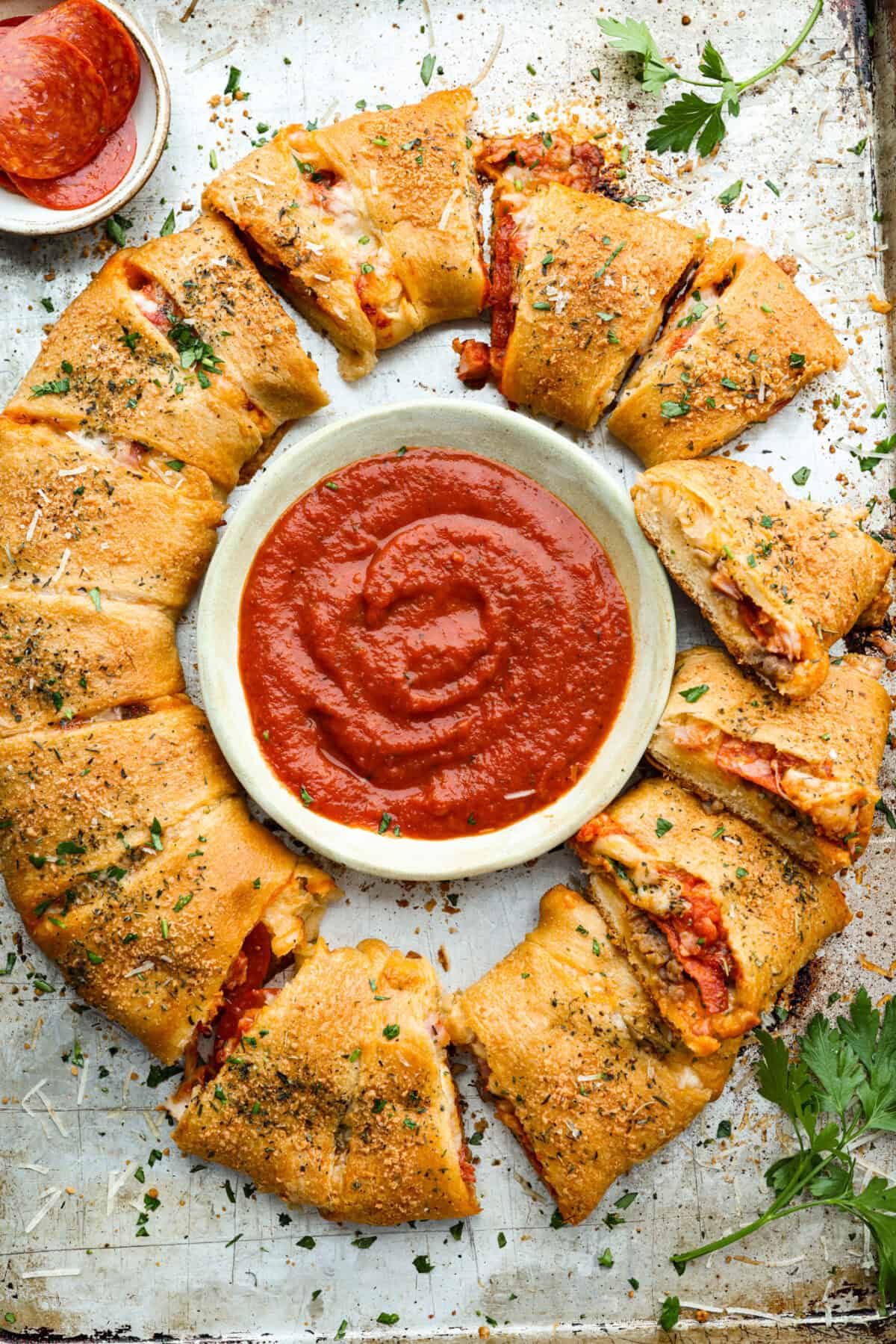 Pizza night just got a glow-up! This fun pull-apart pizza ring is perfect for family dinner, game day, or a party snack. Easy to make, endlessly customizable, and totally kid-approved, you’ll be reaching for slice after slice! Overhead shot of the baked pizza ring with a bowl of marinara sauce in the middle.