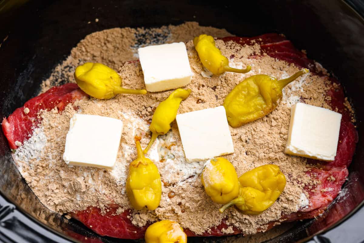 Chuck roast covered in the seasoning packets, butter, and peppers. 