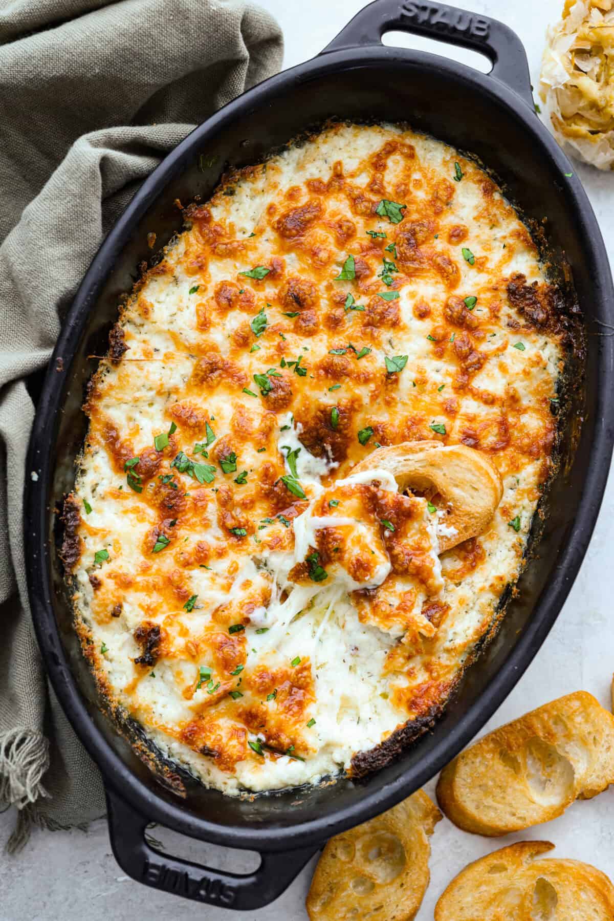 Cheesy garlic bread made into the dip of your dreams! This Garlic Bread Dip is full of roasted garlic and layers of melty cheese. It's irresistible from the very first bite! Overhead shot of the baked cheesy garlic bread dip.