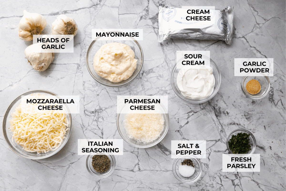 Cheesy garlic bread made into the dip of your dreams! This Garlic Bread Dip is full of roasted garlic and layers of melty cheese. It's irresistible from the very first bite! Overhead shot of labeled ingredients.