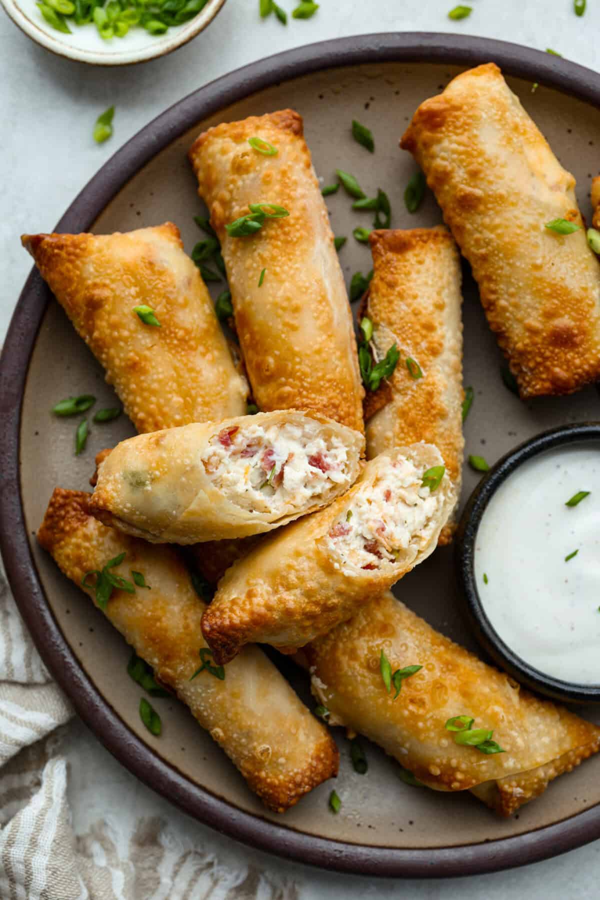 Platter of crack chicken egg rolls with a small bowl of dipping sauce. 
