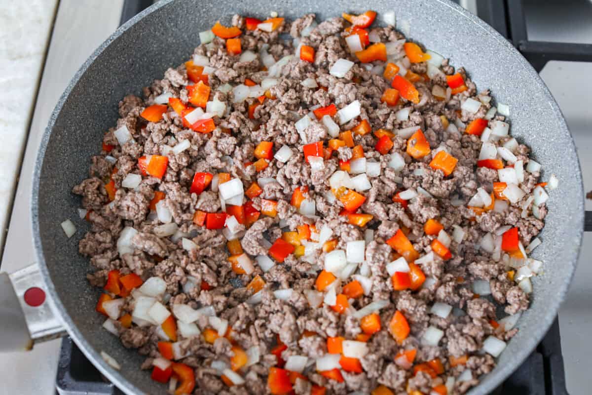 Ground beef, onions and bell pepper cooking in a skillet. 
