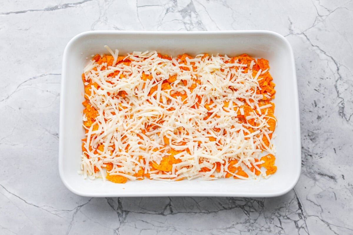 Chips and cheese layered in the bottom of a baking dish.
