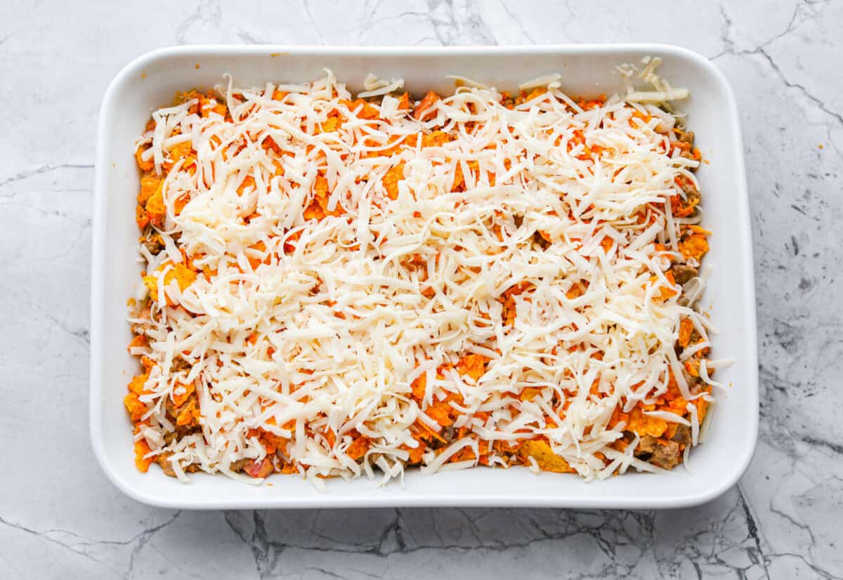 Chips and cheese on top of the meat mixture in the baking dish. 