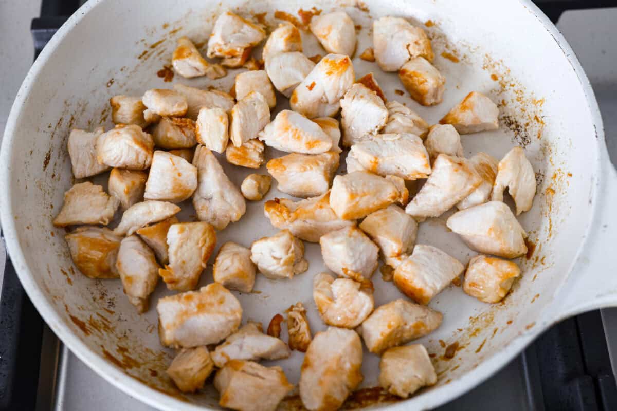 Cubed chicken cooking in a skillet.