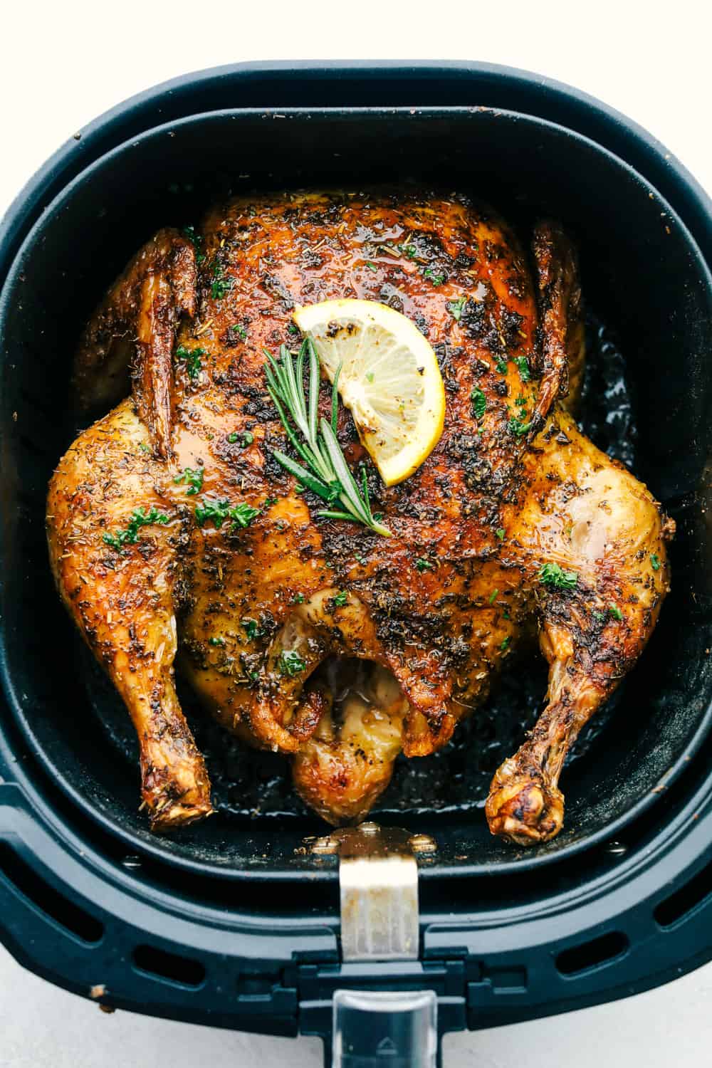 A whole chicken in an air fryer basket. 