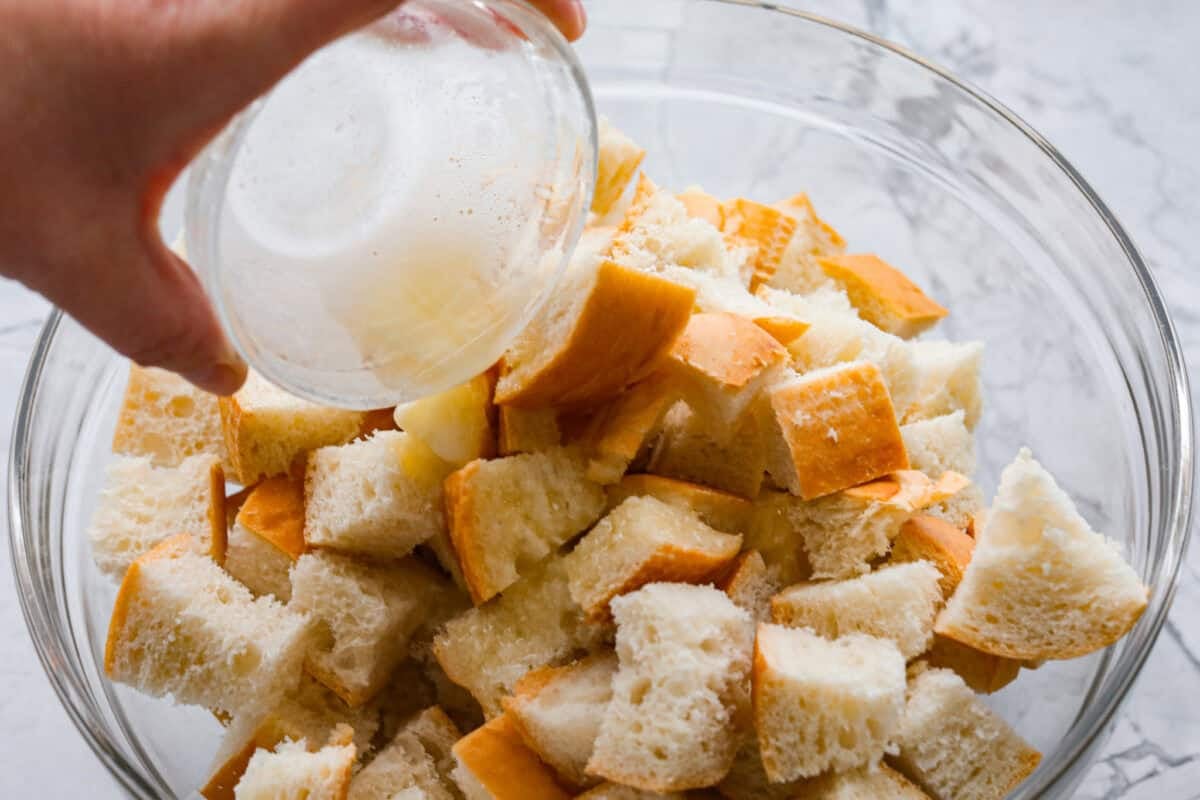 Someone pouring melted butter over the dried bread.