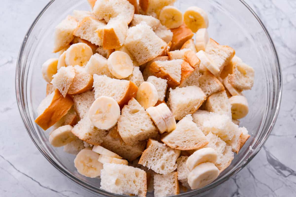 Sliced banana added to the bowl of bread. 