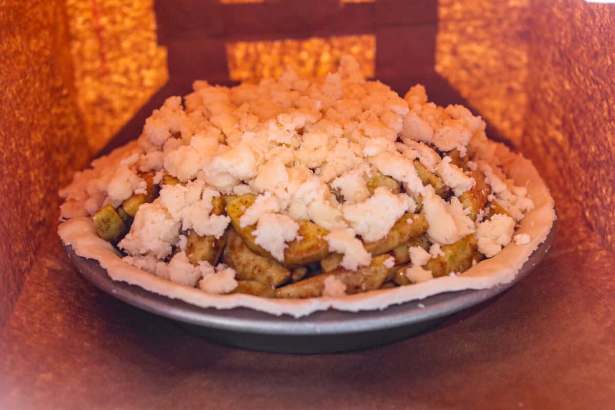Topping added on top of the brown bag apple pie filling and the whole pie placed inside a paper bag.