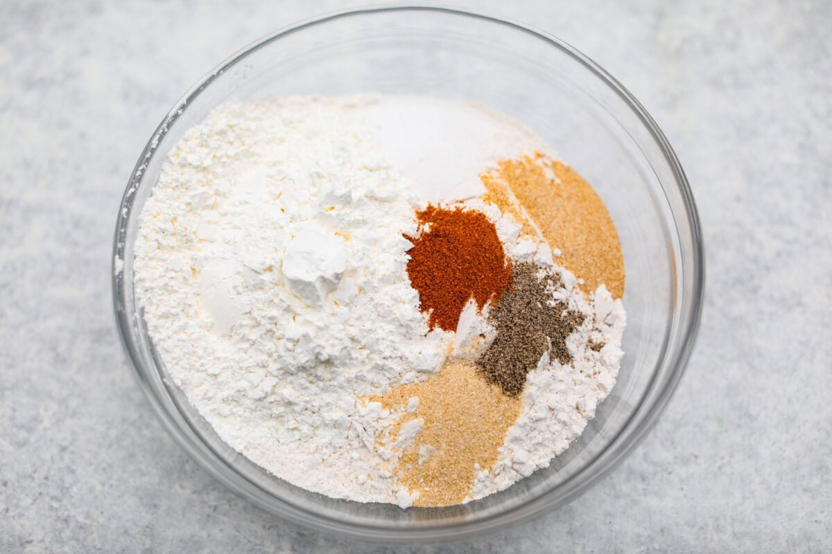 Flour and seasonings added to a mixing bowl. 
