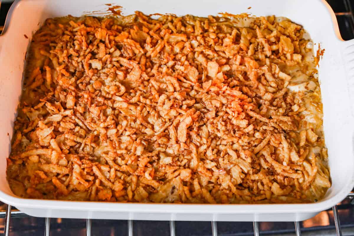 Picture of french onion chicken casserole in the oven with crispy onions added to the top. 