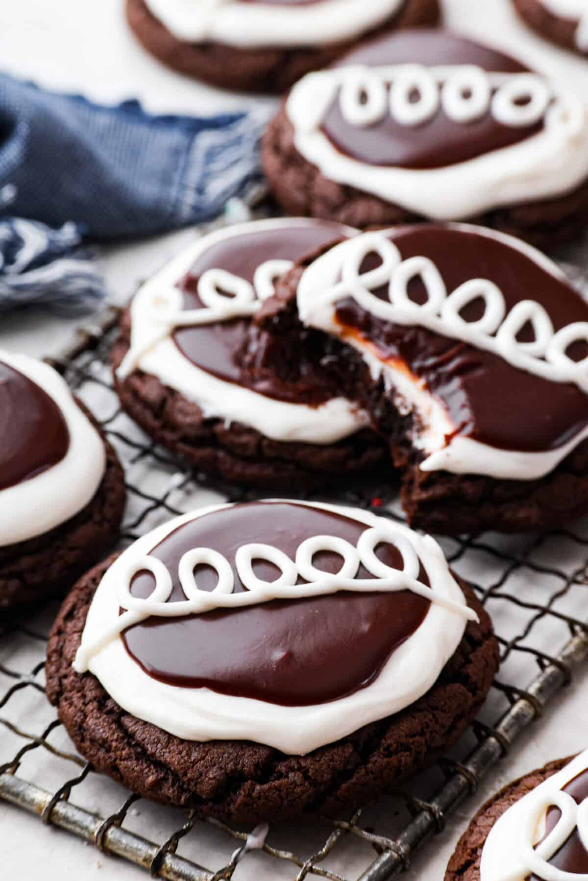 Close up shot of Hostess Cupcake cookies on a wire rack, with one missing a bite. 