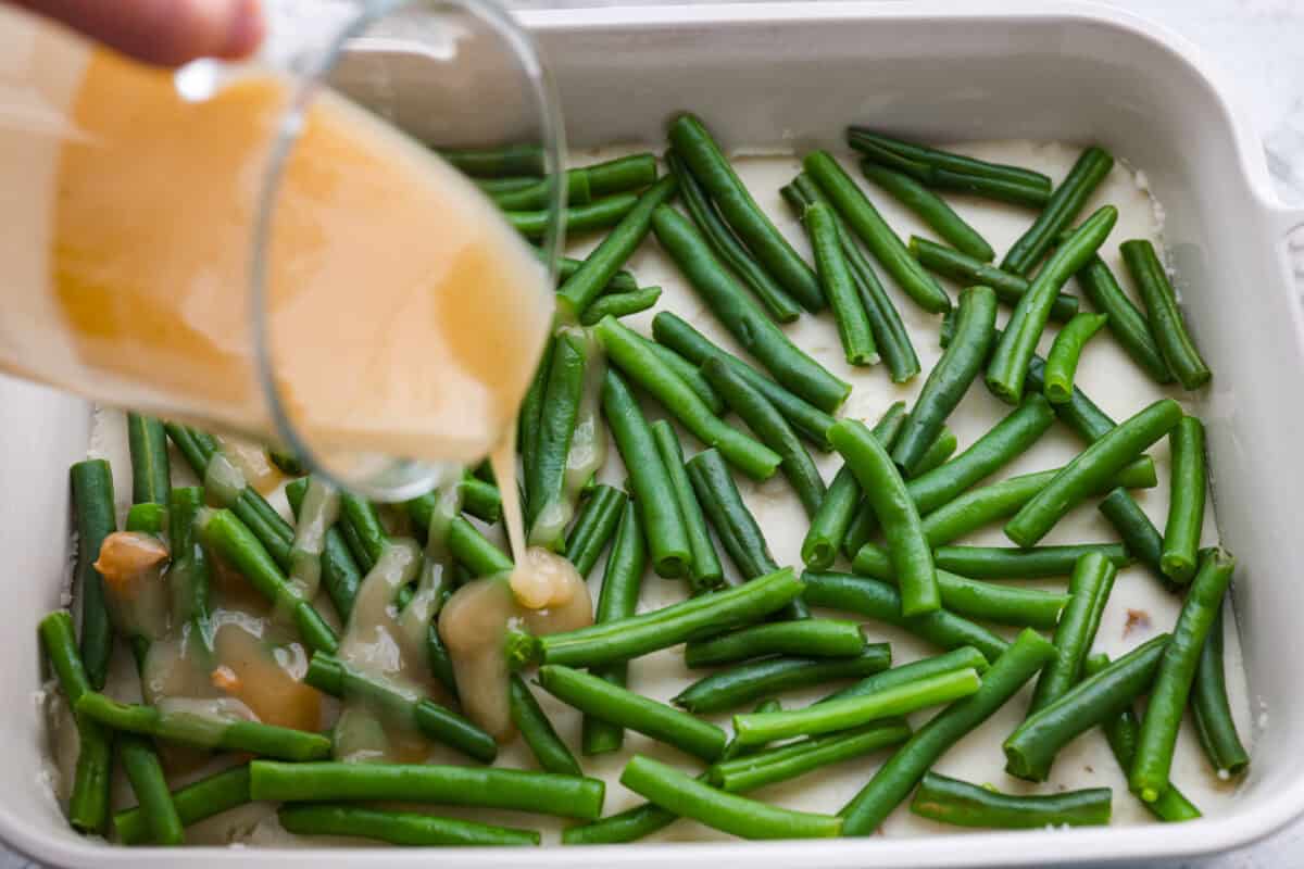 Gravy being poured over the top of the green beans. 