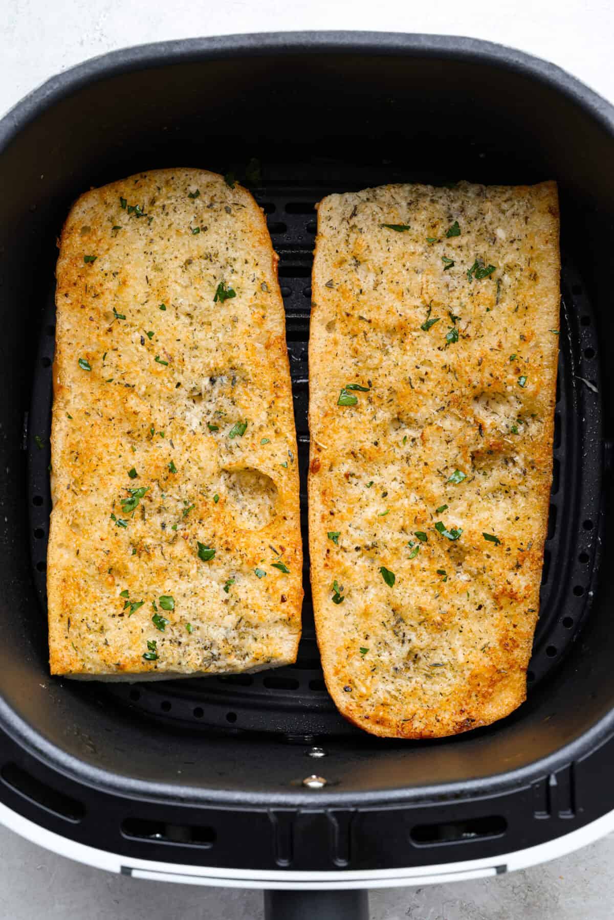 Overhead shot of air fryer garlic bread cooked and in the air fryer basket. 