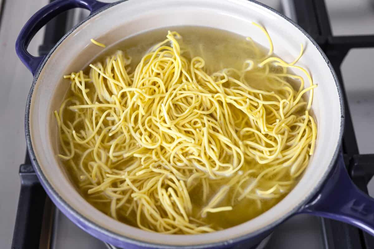 Chow mein noodles cooking in a pot on the stove. 