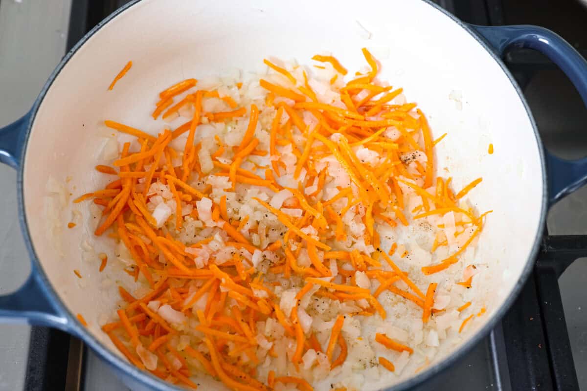 Onions, carrots, and garlic cooking in a pan.