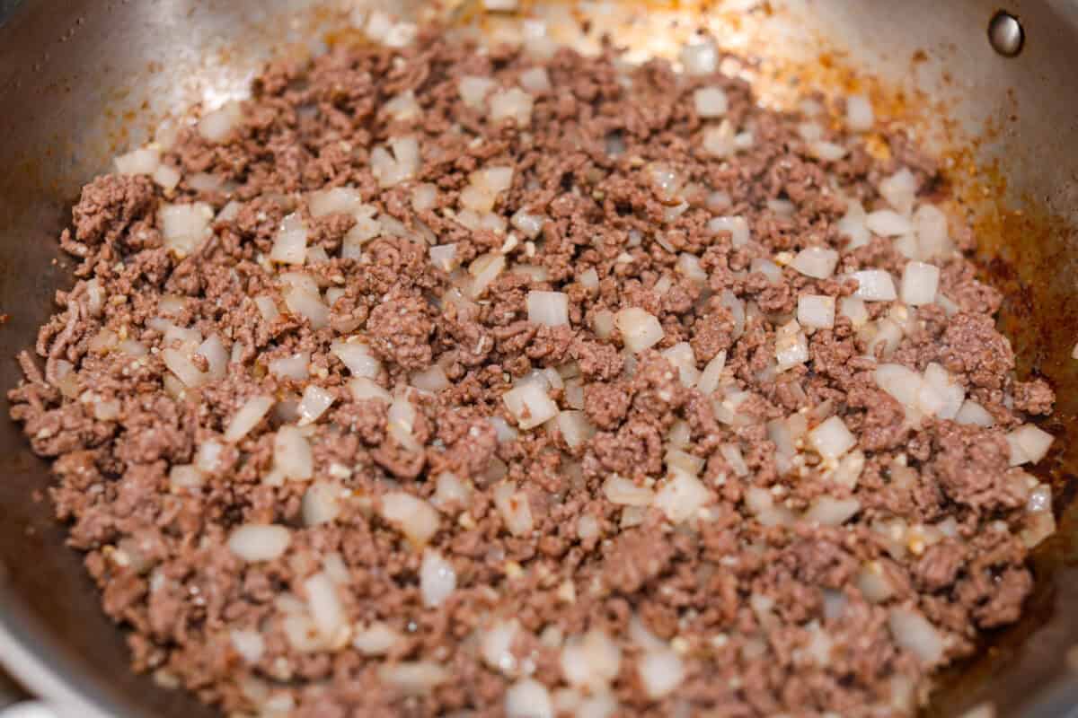 Ground beef ad onions cooking in a skillet.