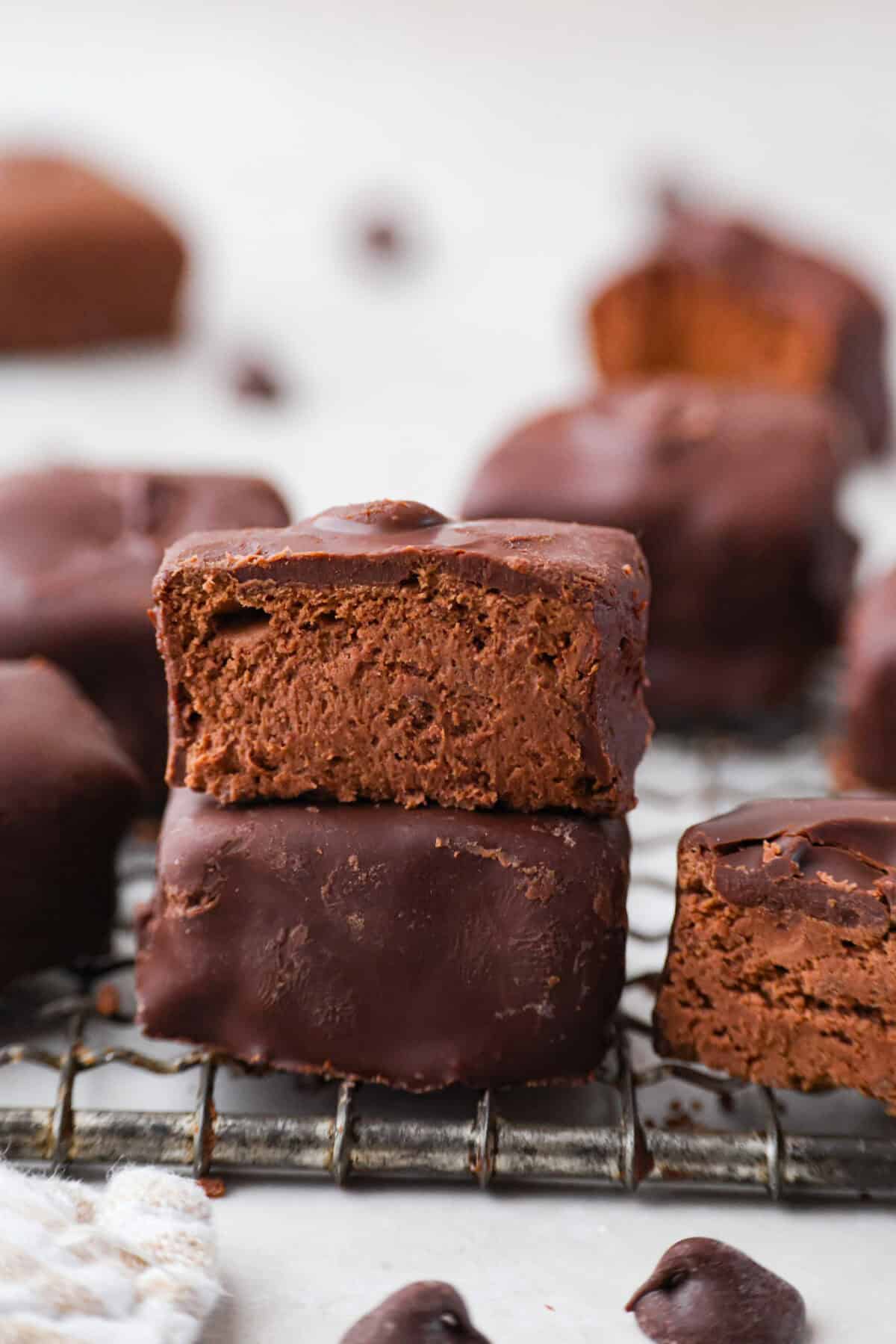 This 3 Ingredient Cool Whip Candy tastes just like a Three Musketeers! Fluffy on the inside, smooth chocolate on the outside, and so easy to make. It is the kind of treat you stash in the freezer and keep sneaking for yourself! Two pieces of cool whip candy stacked on top of each other and the top one is cut in half.