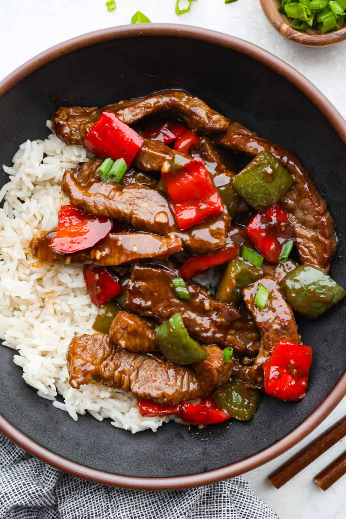 Plated serving of pepper steak over a bed of white rice. 