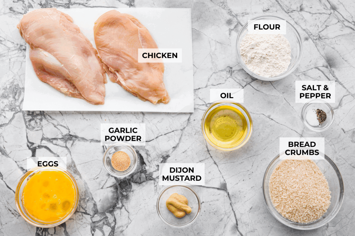 Overhead shot of labeled chicken schnitzel ingredients. 
