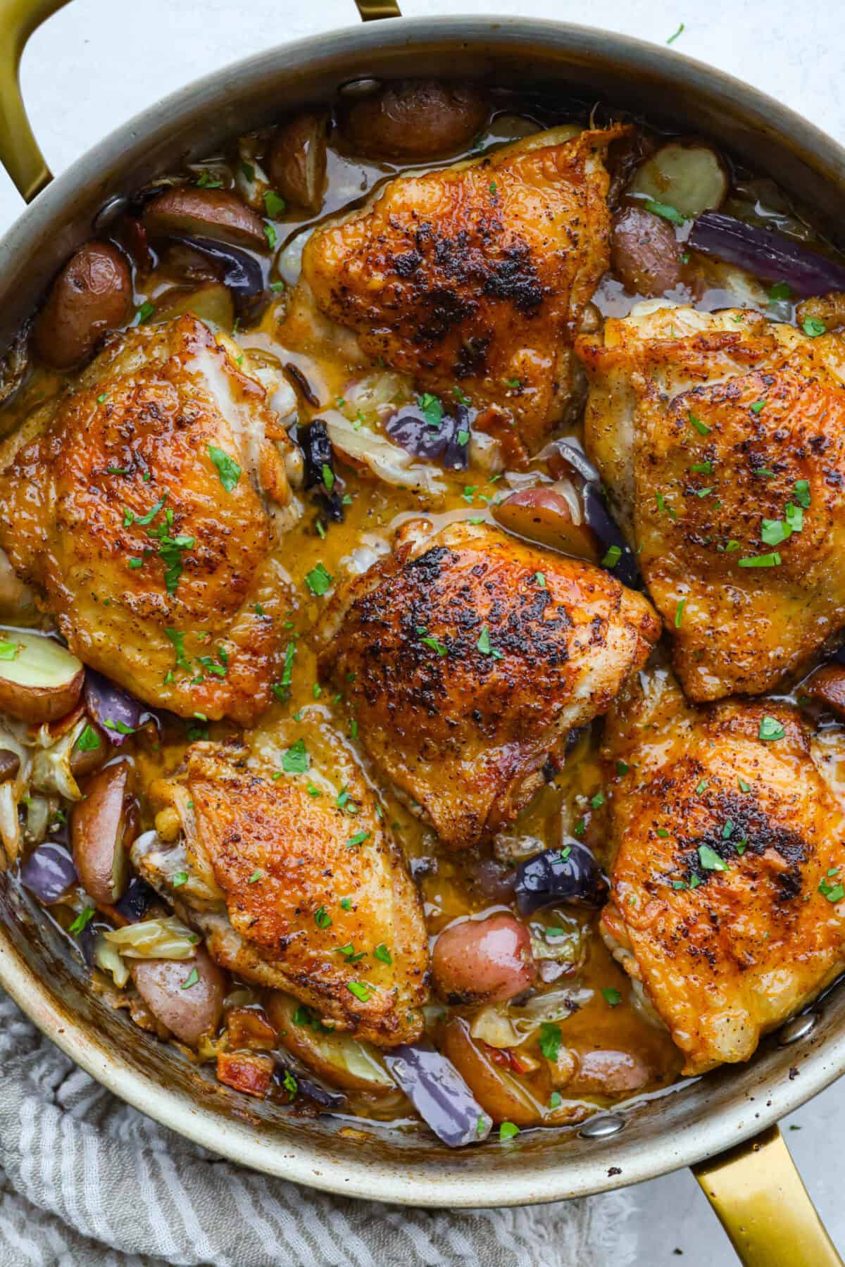 This Irish chicken is my cozy mashup of pub vibes and weeknight reality. Seared chicken thighs baked over bacon, cabbage, and potatoes, then I add a splash of Irish whiskey and a touch of cream to make the whole pan taste extra special. skillet of cooked and ready to eat Irish chicken.