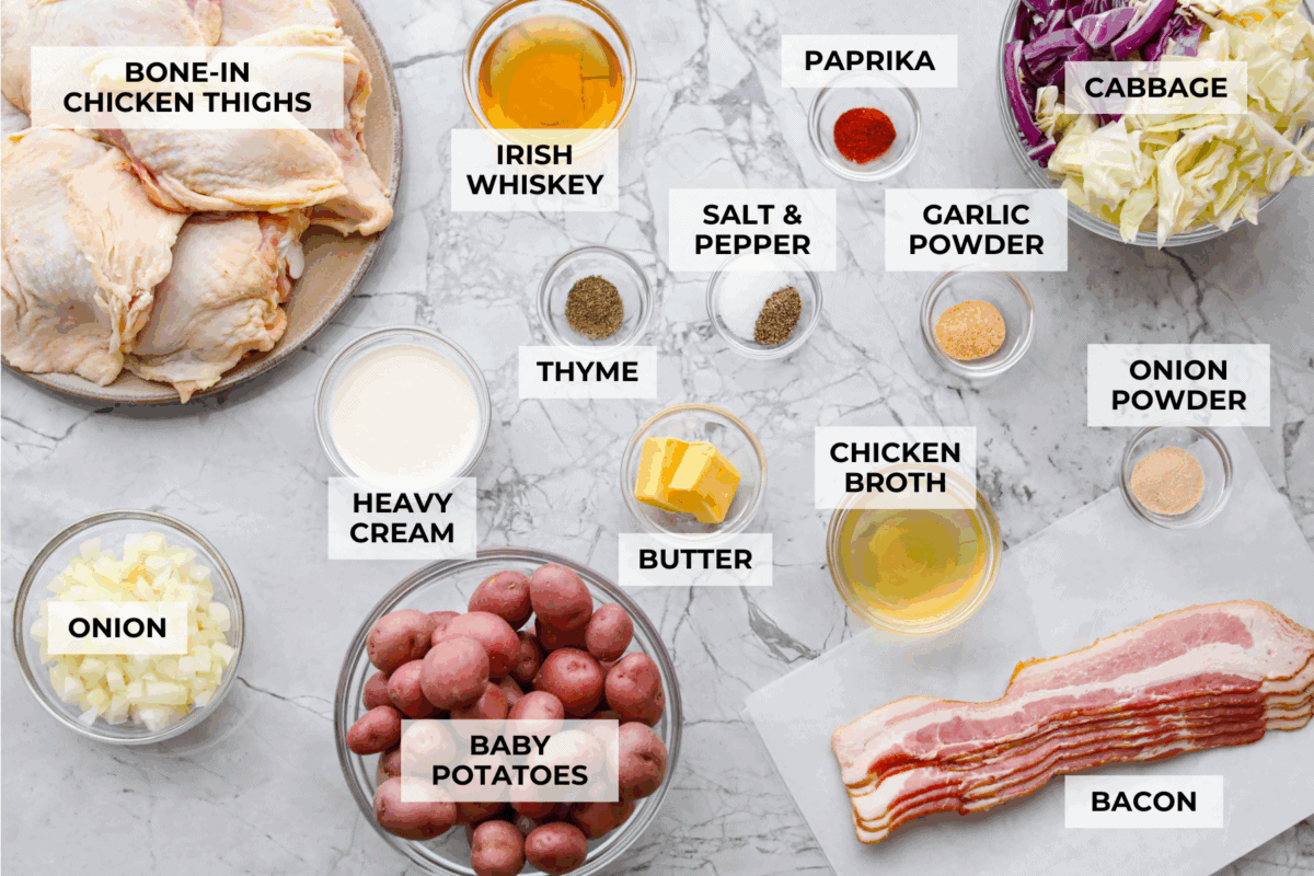 This Irish chicken is my cozy mashup of pub vibes and weeknight reality. Seared chicken thighs baked over bacon, cabbage, and potatoes, then I add a splash of Irish whiskey and a touch of cream to make the whole pan taste extra special. Overhead shot of labeled Irish chicken ingredients.