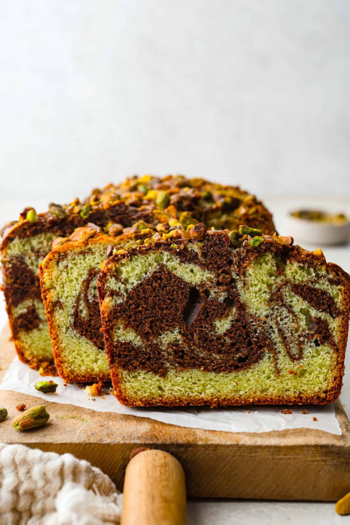 Side view of sliced chocolate pistachio loaf on a cutting board. 