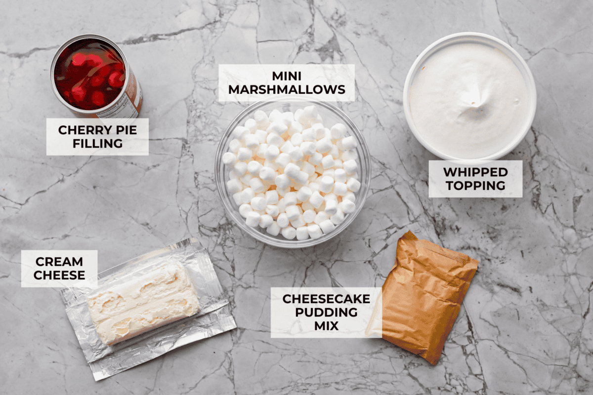 Fluff salads never go out of style. They're light, creamy, and just plain fun! This cherry cheesecake fluff is customizable and so easy to throw together! It's packed with sweet-tangy cheesecake flavor and juicy cherries in every bite. Overhead shot of labeled ingredients.