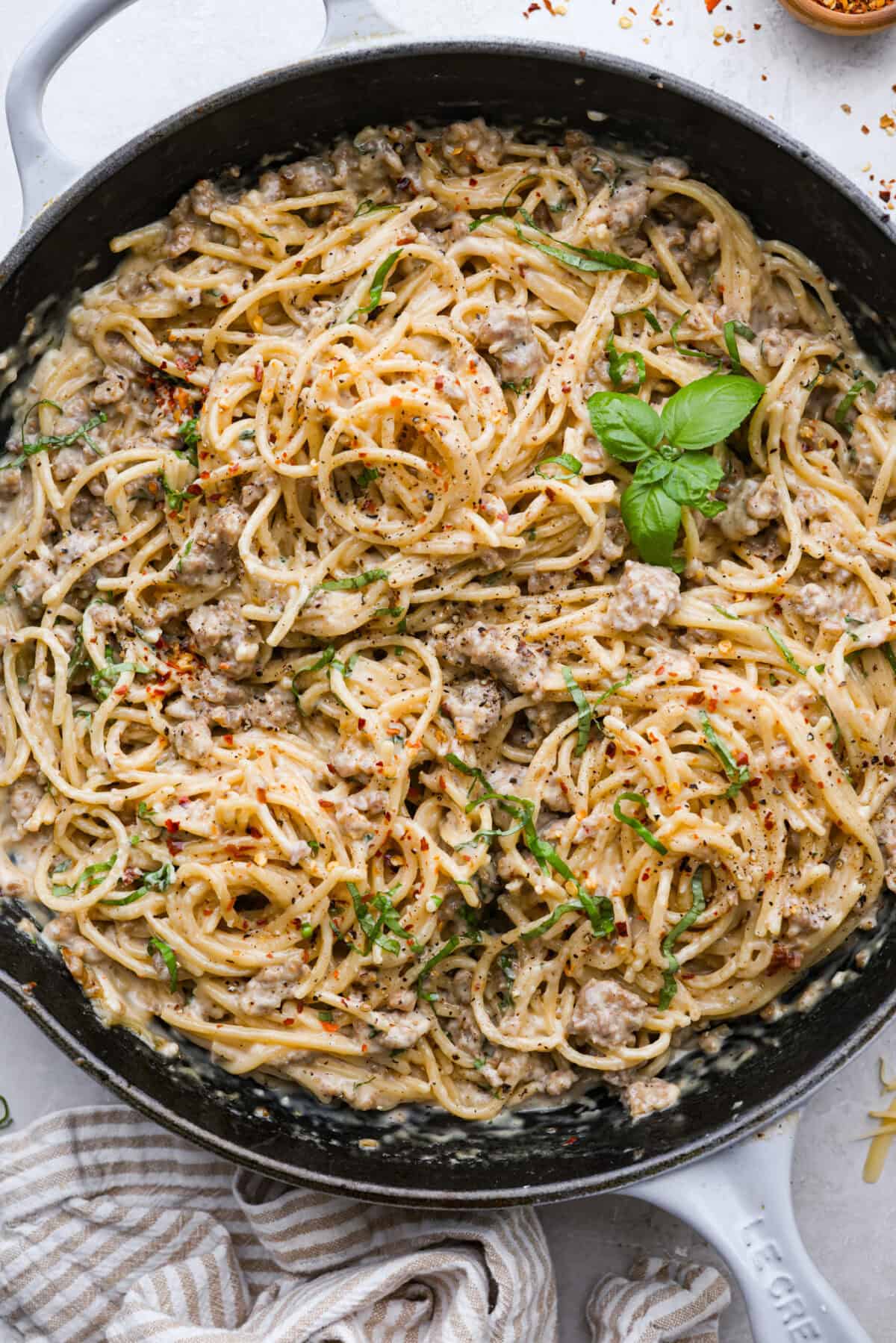 If you love a creamy pasta with big flavor, this creamy sausage spaghetti needs to be on your menu. Smoked Gouda adds depth, the sausage brings a little heat, and fresh basil adds brightness. Simple ingredients, quick to make, and always a hit! Overhead shot of the skillet full of cooked creamy sausage spaghetti ready to serve.