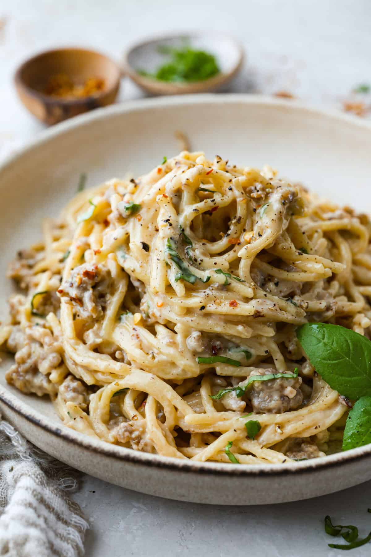 If you love a creamy pasta with big flavor, this creamy sausage spaghetti needs to be on your menu. Smoked Gouda adds depth, the sausage brings a little heat, and fresh basil adds brightness. Simple ingredients, quick to make, and always a hit! Plate of creamy sausage spaghetti garnished with basil leaves.