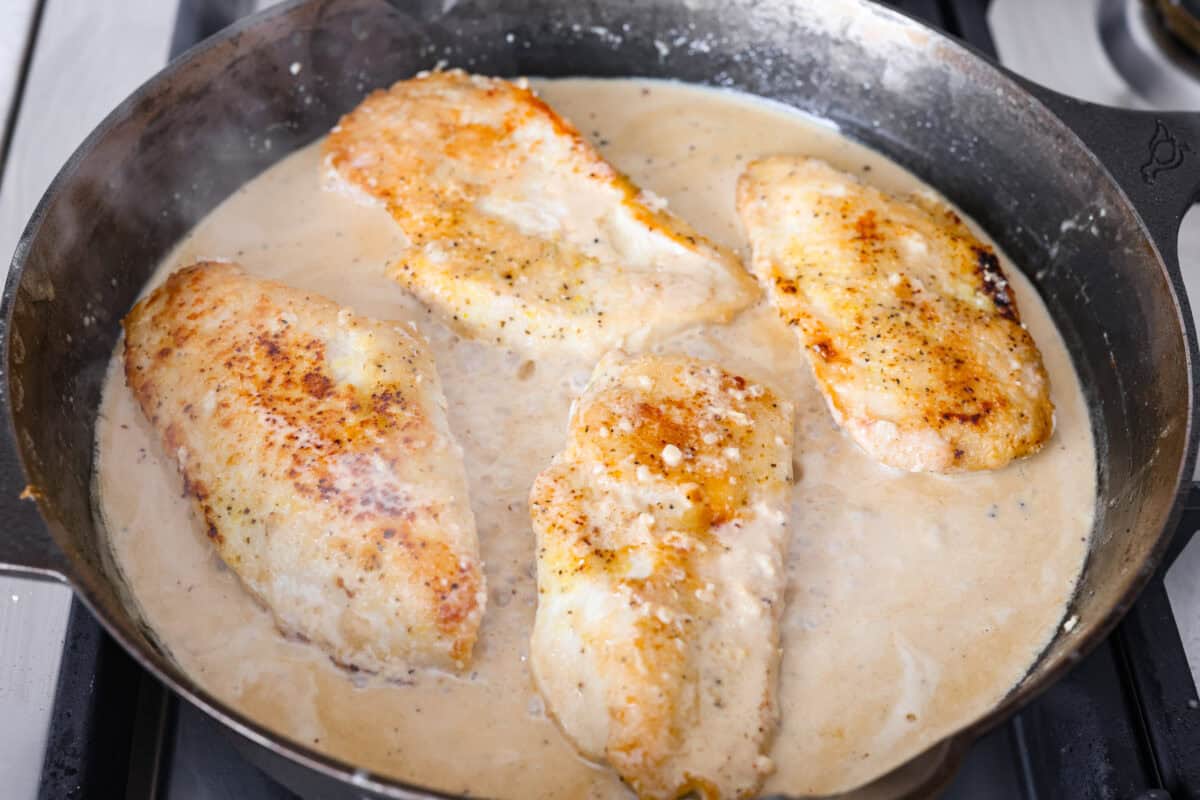 This lemon butter chicken is about to become your new weeknight secret weapon. One skillet, simple ingredients, and less than 30 minutes to the most golden, saucy, creamy chicken you've ever made. Chicken breasts added to the sauce in the skillet.