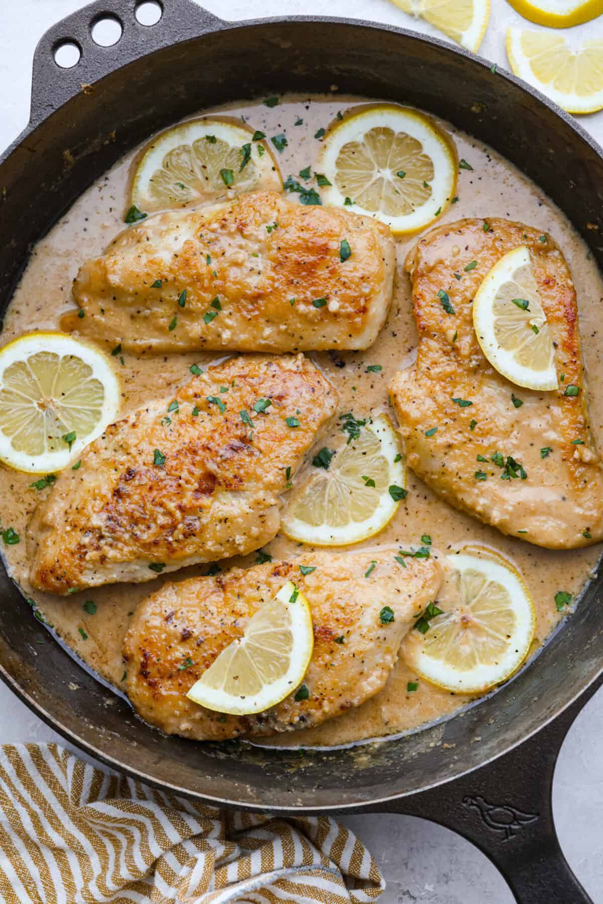 This lemon butter chicken is about to become your new weeknight secret weapon. One skillet, simple ingredients, and less than 30 minutes to the most golden, saucy, creamy chicken you've ever made. Lemon butter chicken in a skillet with slices of lemon and fresh parsley.