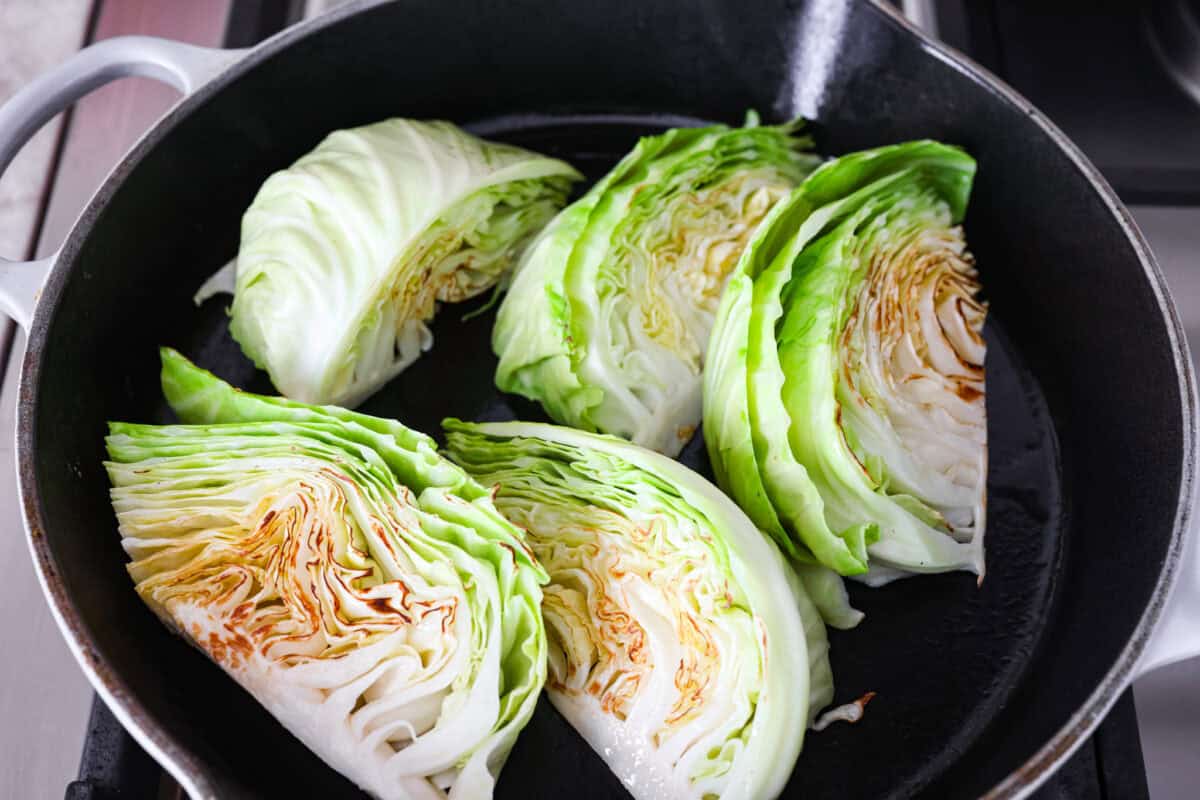 Cabbage wedges browning in a skillet. 