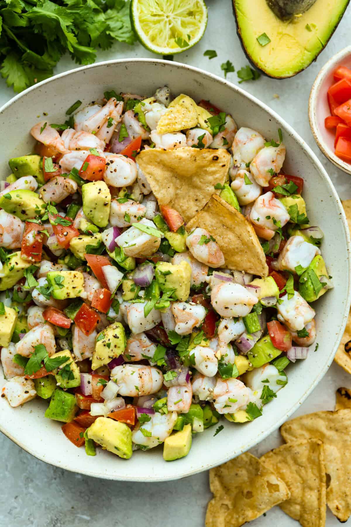 If you're anything like me, you LOVE shrimp ceviche! My version has avocado and is fresh, bright, and has the most incredible flavor. It's the perfect no-cook dish for warm weather. Make it, trust me, you will thank me later! Bowl of shrimp ceviche with a couple of tortilla chips garnishing it.