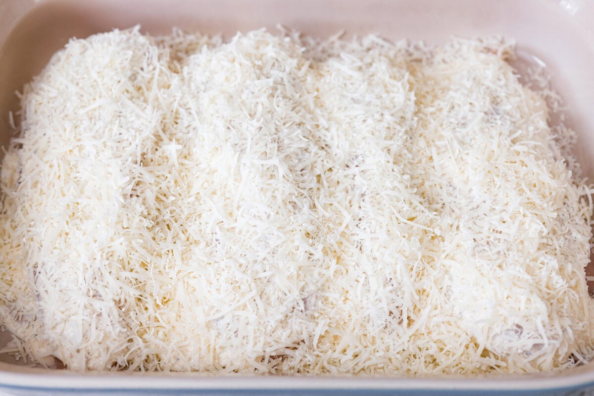 My Caesar chicken bake turns classic Caesar salad flavors into an easy one-pan dinner! Juicy chicken is smothered in creamy dressing, topped with parmesan and buttery crushed croutons, and baked to golden, cheesy perfection. Parmesan cheese covering the tops of the caesar dressing covered chicken breasts.