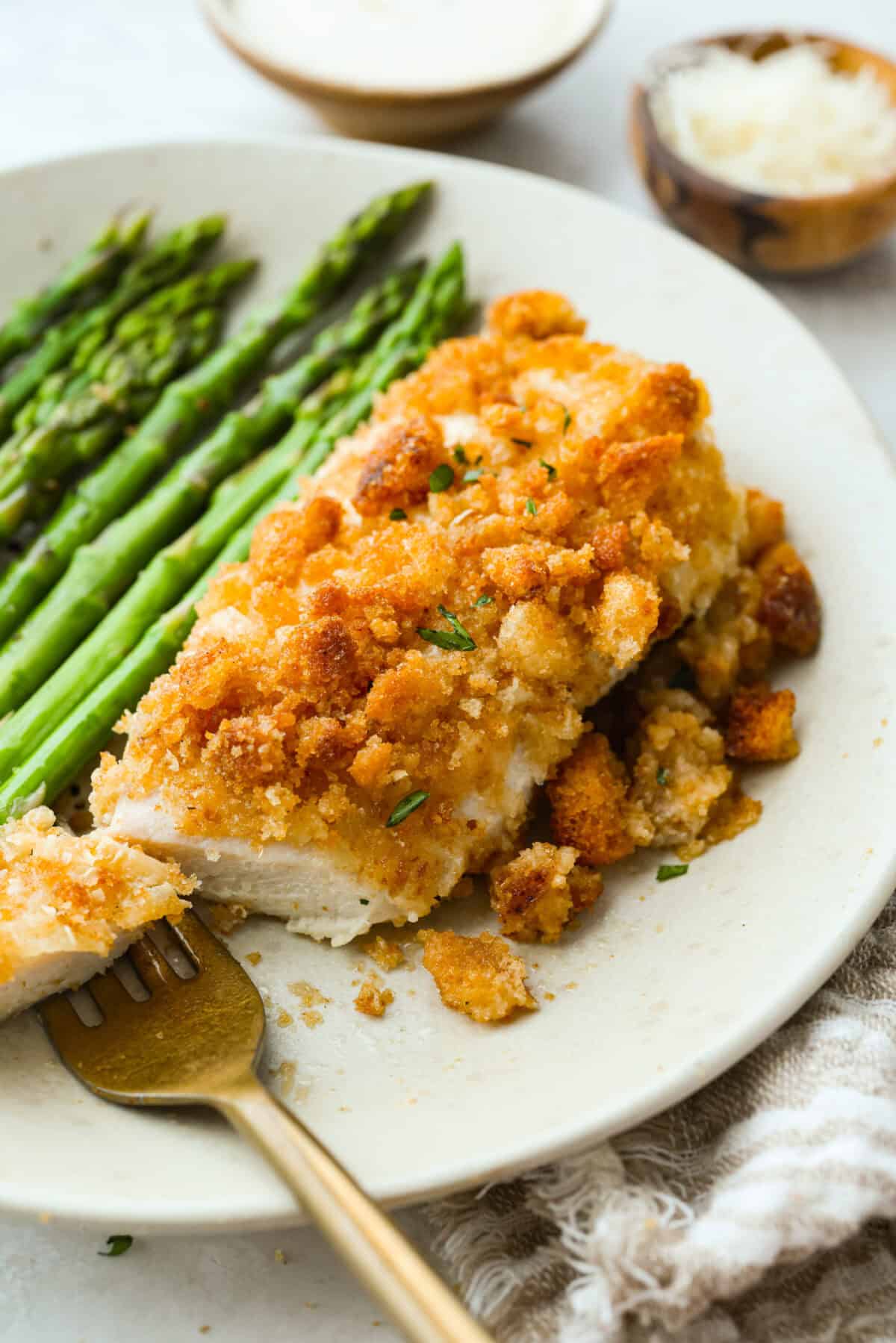 My Caesar chicken bake turns classic Caesar salad flavors into an easy one-pan dinner! Juicy chicken is smothered in creamy dressing, topped with parmesan and buttery crushed croutons, and baked to golden, cheesy perfection. Plated caesar chicken salad bake with asparagus.