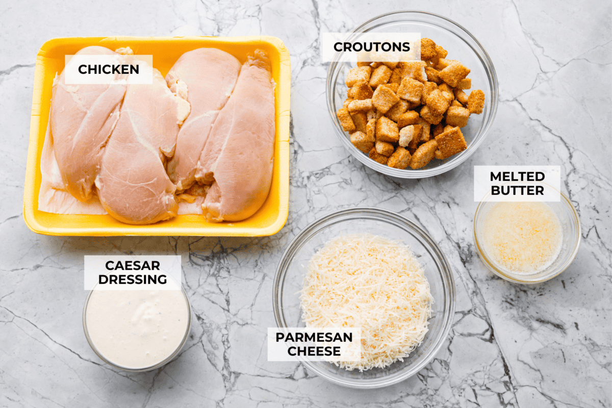 My Caesar chicken bake turns classic Caesar salad flavors into an easy one-pan dinner! Juicy chicken is smothered in creamy dressing, topped with parmesan and buttery crushed croutons, and baked to golden, cheesy perfection. Overhead shot of labeled ingredients.